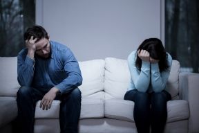 Husband and wife sitting separately on a couch representing legal separation 